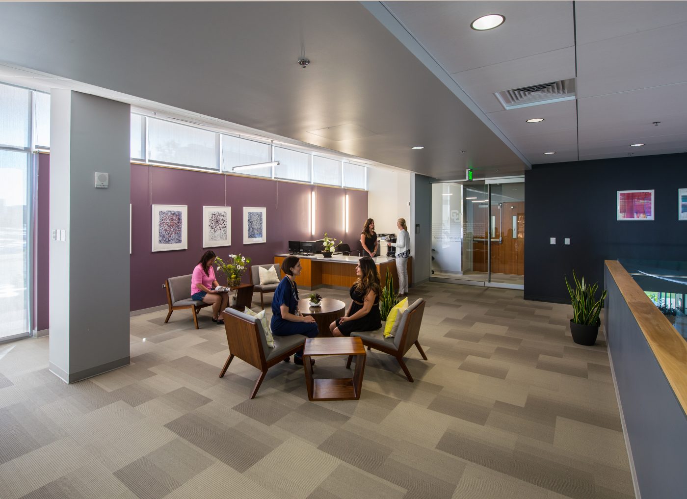 Modern office waiting area with people, reception desk, and contemporary art in Denver.